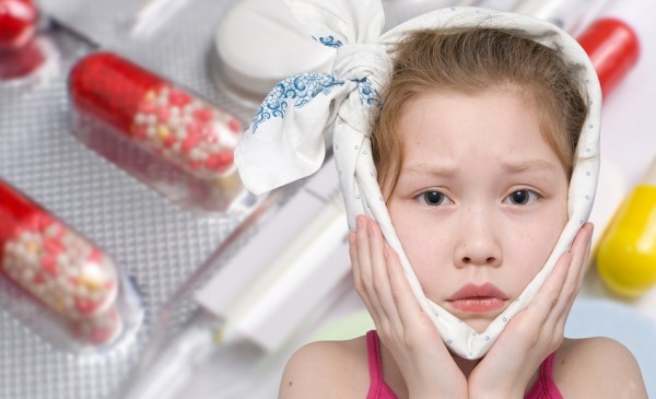 a girl with a bandage around her face, various pills and a glass thermometer in the background