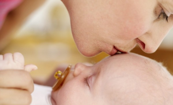 Woman Kissing the Top of a Baby's Head (3-6 Months) --- Image by © Royalty-Free/Corbis