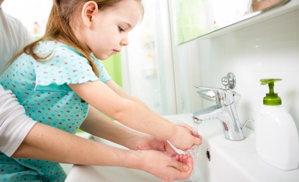kid girl washing hands with mom help