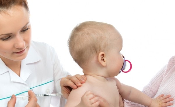 Doctors hand with syringe vaccinating child baby flu injection shot isolated on a white background