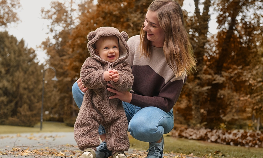 Mama su vaiku, apsirengusiu meškiuko kombinezonu